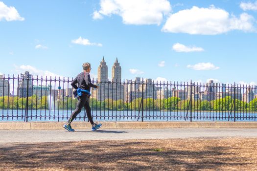NEW YORK, USA - 15 MAY, 2019: Jogger running along Central Park reservoir in New York. Central Park is full of active people throughout the year.