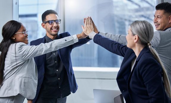 Dedicated to shared goals and big results. Shot of a group of businesspeople giving each other a high five in an office.