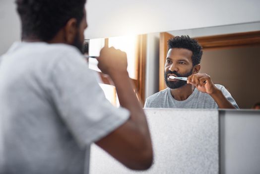 Hes a firm believer in brushing twice a day. Cropped shot of a handsome young man brushing his teeth in the bathroom at home.