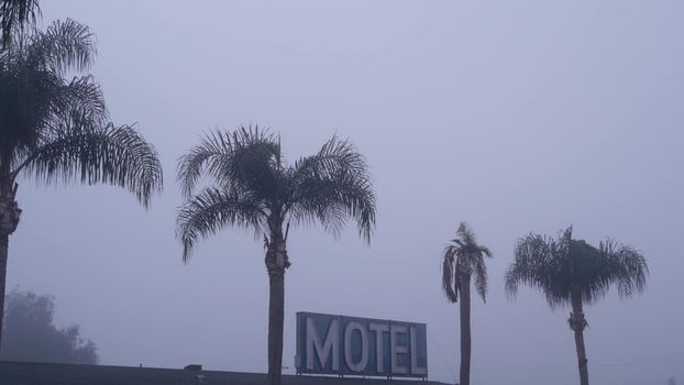 Sign of road motel or hotel, foggy misty weather California, USA. Palm trees.