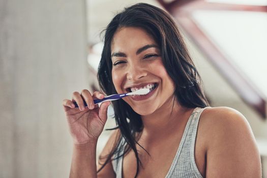 Fresh breath to start off a new day. Portrait of an attractive young woman brushing her teeth at home.