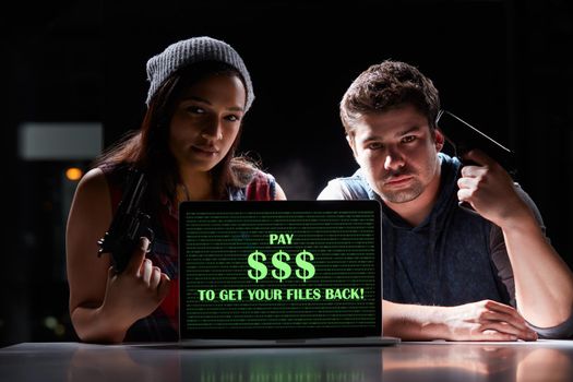 Give us the money and no one gets hurt. Shot of two armed hackers using a laptop with Pay $$$ to get your files back on it.