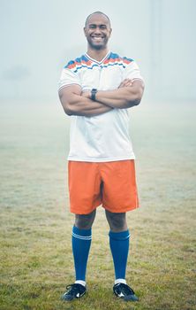 I take pride in my team. Shot of a young sportsman standing on the field during a misty morning.