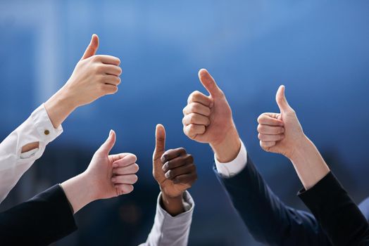 Teamwork trumps all. Shot of a group of office workers giving thumbs up together.