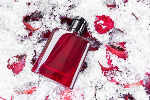Perfume bottle on red leaves covered by snow background. Packaging design mockup. Branding identity..