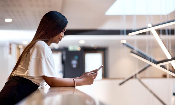 A busy day of networking deserves a break. Shot of a young businesswoman using a smartphone at a conference.