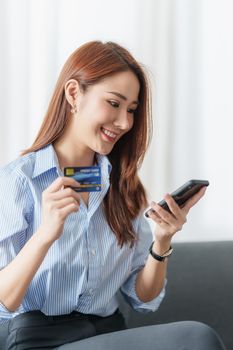 Woman using shopping application by cell phone and payment by credit card.