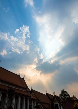 Sun beam behind the sunset clouds over the buddhist temple