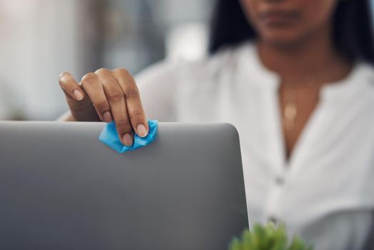 Be sure to disinfect the items you regularly use. Closeup shot of an unrecognisable businesswoman cleaning a laptop in an office.