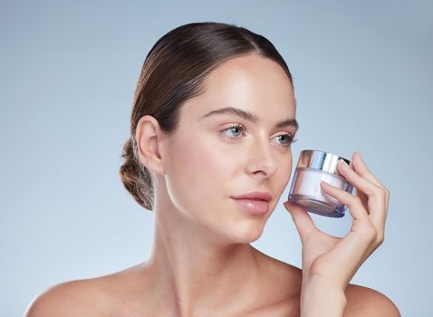 Shes always got skincare on the mind. Cropped shot of an attractive young woman posing with a container of moisturizer against a grey background.