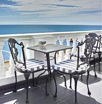 What a view. Tables and chairs on the balcony of a seaside restaurant.