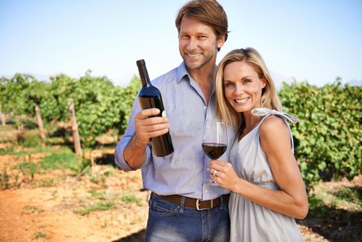 Enjoying a day of wine tasting among the vines. Portrait of a couple enjoying wine tasting in a vineyard.