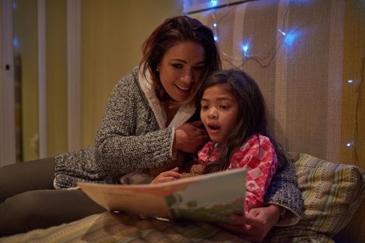Open a book and you open their imagination. Shot of mother reading a bedtime story with her daughter at bedtime.