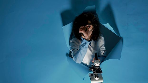 Crazy foolish scientist using laboratory microscope in studio