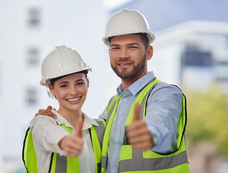 Everything is up to code. Cropped portrait of two young construction workers giving thumbs up while standing on site outside.