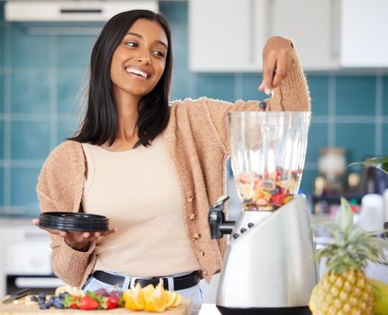Loading her smoothie with lots of fresh ingredients. Shot of a young woman preparing a healthy smoothie at home.