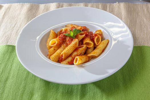 Serving of spicy savory italian penne pasta garnished with fresh basil