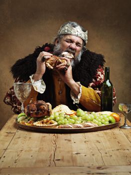 Ruling is hungry business. A mature king feasting alone in a banquet hall.