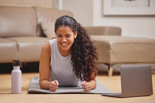 The longest minute in history is felt when doing a plank. Shot of an attractive young woman using her laptop to follow an online fitness class in her living room.