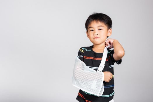Little cute kid boy 5-6 years old hand bone broken from accident with arm splint in studio shot isolated
