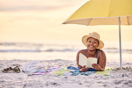 Serenity that speaks volumes. Portrait of a beautiful young woman relaxing with a book at the beach.