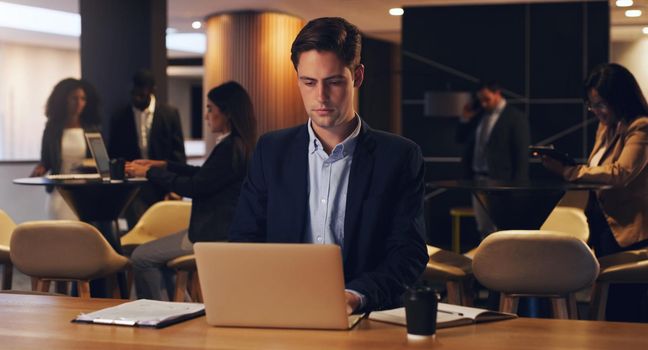 The rewards for your dedication will be great. Shot of a young businessman working on a laptop in an office at night.