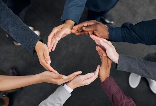 A representation of unity. Shot of a group of businesspeople with their hands joined together to form a circle.