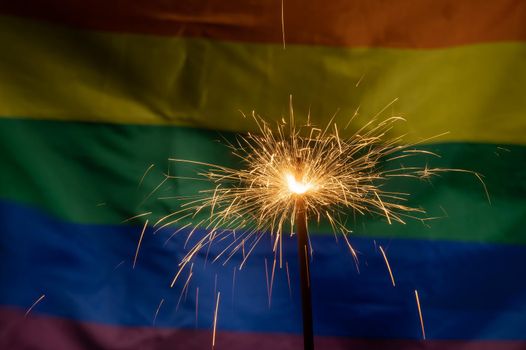 Sparklers with waving lgbt rainbow flag background.