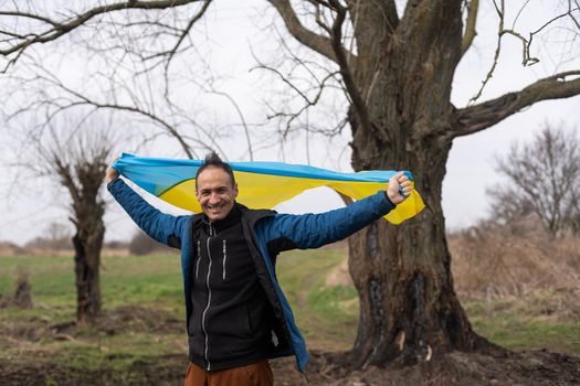 successful silhouette man winner waving Ukrainian flag near a burnt tree