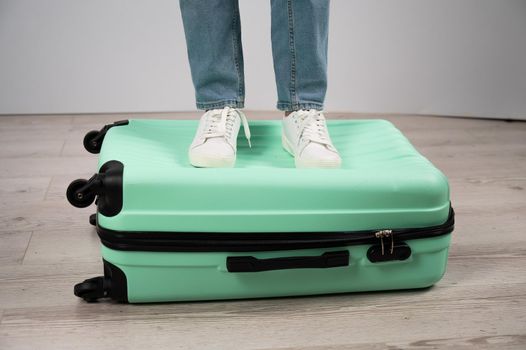 Woman standing with her feet on a suitcase.