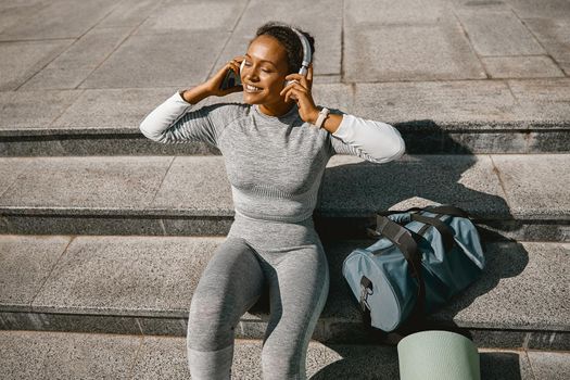 Excited active woman in sportswear relaxing outdoors after exercising