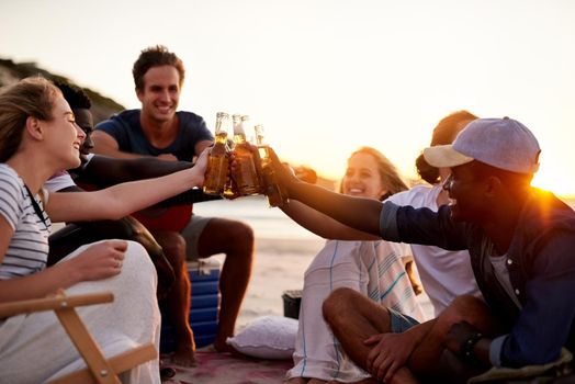 Cheers to friends who became family. Shot of a group of friends enjoying drinks on the beach.