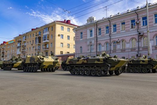 Russian military vehicles on the city street against the backdrop of residential buildings. Russian modern military tank, infantry fighting vehicle BMP and armored personnel carrier BTR.