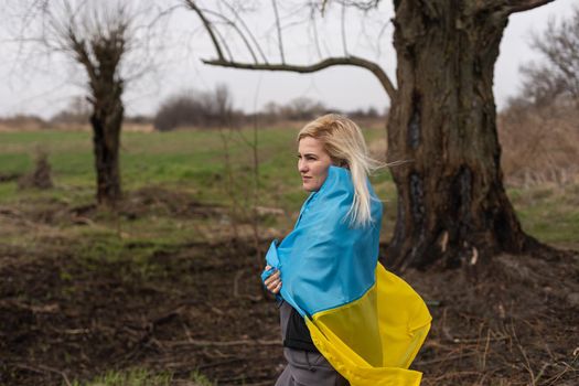 woman flag of ukraine near burnt tree
