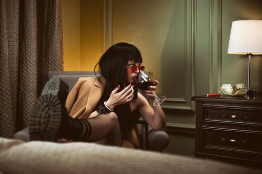 female criminal in a hotel drinking wine