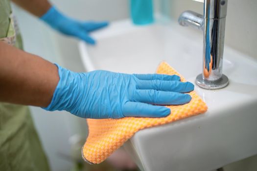 Maid cleaning wash and scrub basin in toilet at home.