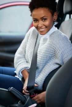 Always buckle up and keep safe. Portrait of a young woman fastening her seatbelt in a car.