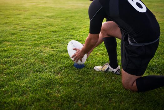 I need to score this. Cropped shot of an unrecognizable sportsman crouching alone during rugby practice in a sports club.