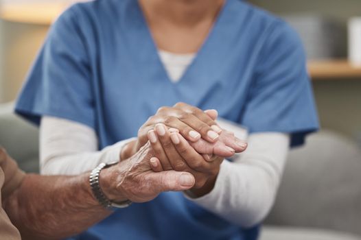 Heroes wear scrubs too. Shot of an unrecognizable nurse holding a patients hand during a checkup at home.