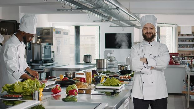 Portrait of male cook sitting in professional gastronomy kitchen