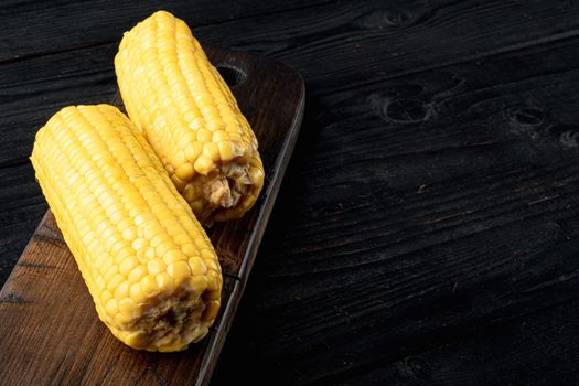 Homemade golden sweet corn cob, on black wooden table background, with copy space for text