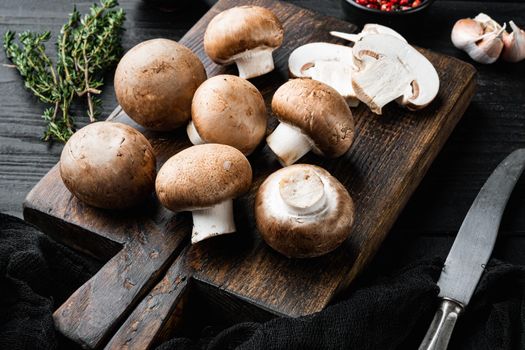 Brown champignons mushroom, on black wooden table background