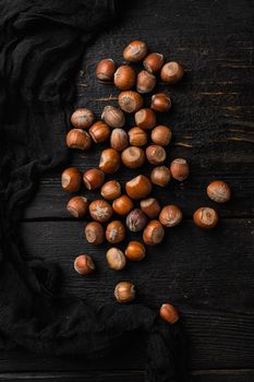 Hazelnuts brown wooden shell, on black wooden table background, top view flat lay