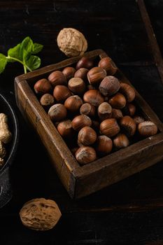 Heap or stack of hazelnuts, on old dark wooden table background