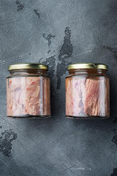 Tuna fillet in glass jar, on gray background, flat lay