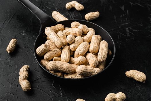Peanuts serving to make oil, peanut butter, on black dark stone table background