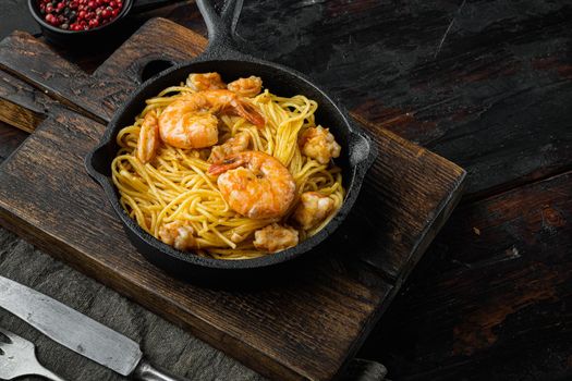 Noodles with seafood, in cast iron frying pan, on old dark wooden table
