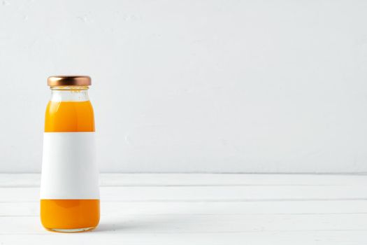 Small glass bottle of fresh juice on white background