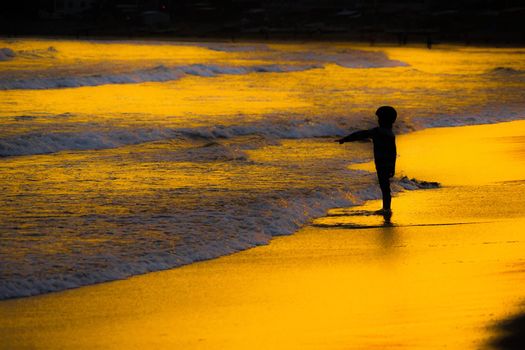 Kid playing at dusk waves