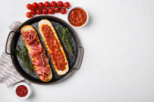 Toasted bread slice with fresh tomatoes and cured ham, on white stone table background, top view flat lay, with copy space for text